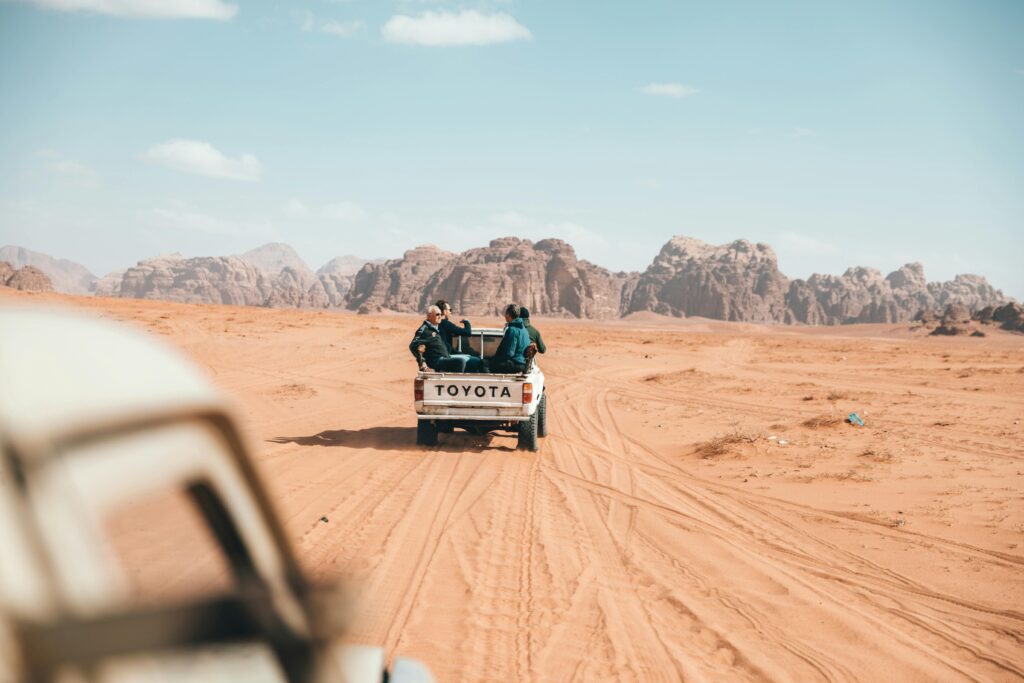 Pickup truck with travelers off-roading in Wadi Rum desert, capturing the essence of adventure in Jordan.