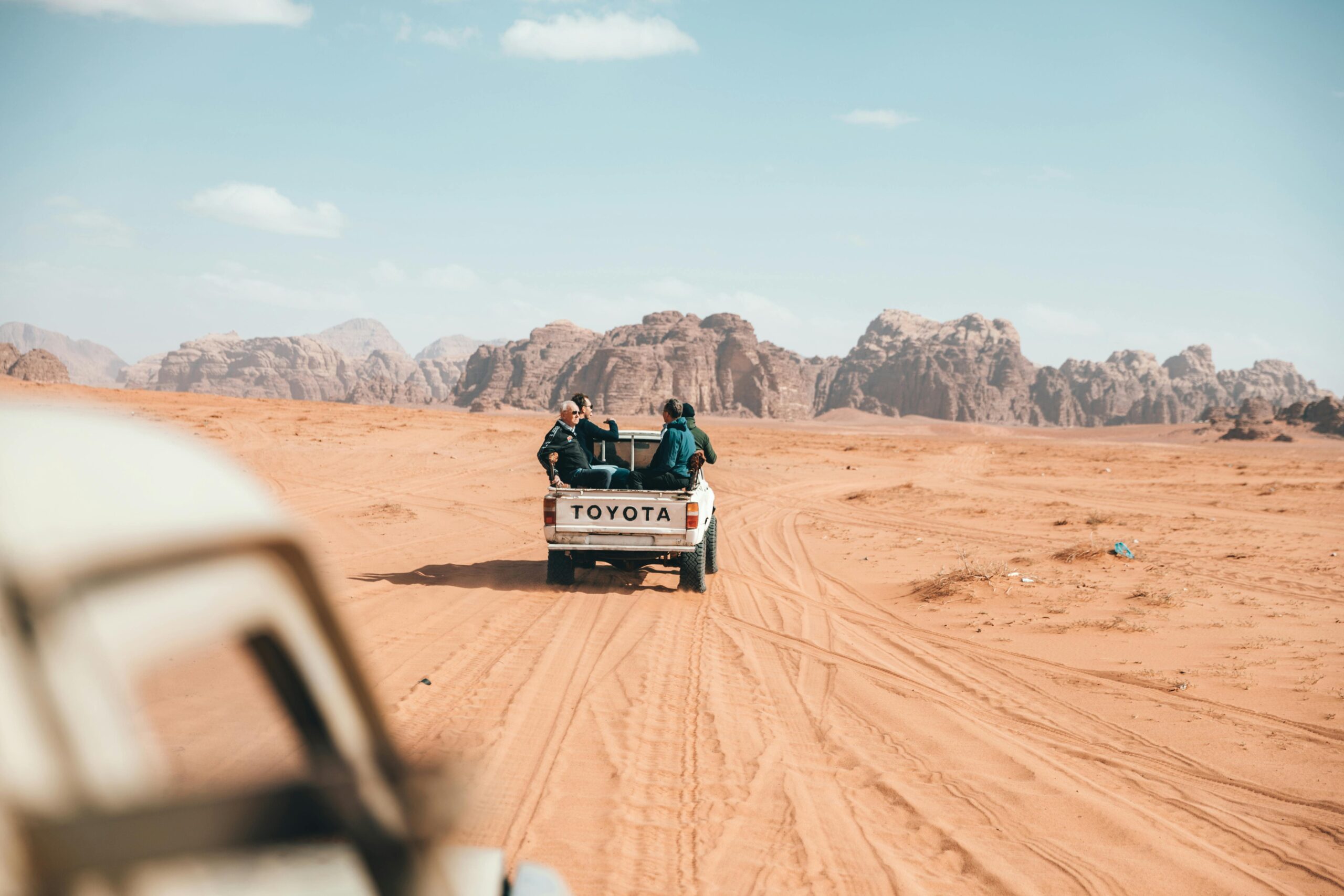 Pickup truck with travelers off-roading in Wadi Rum desert, capturing the essence of adventure in Jordan.